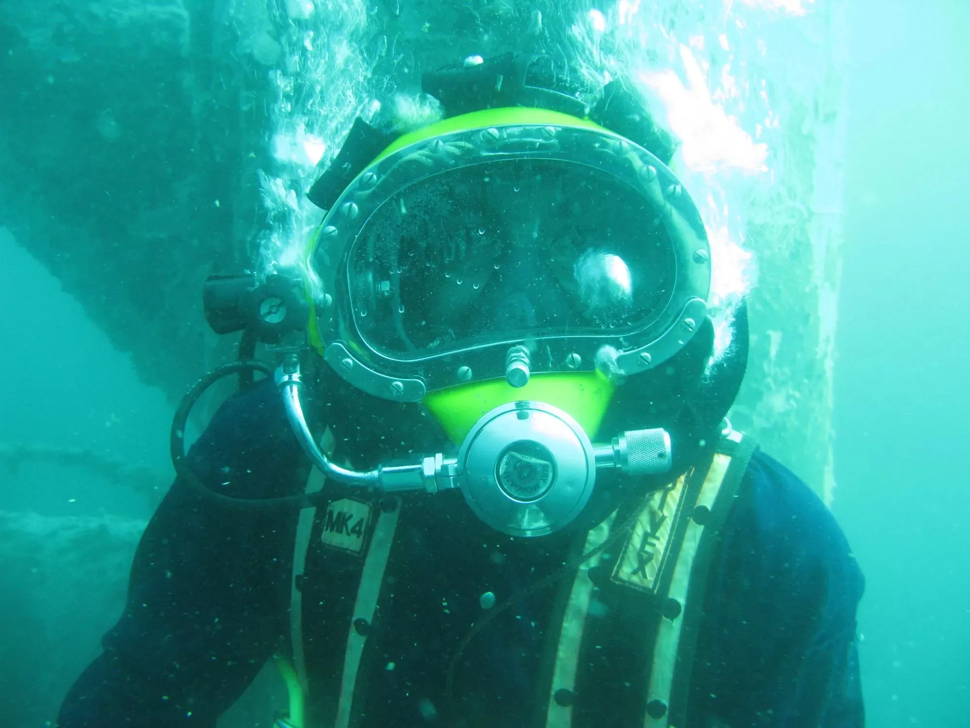 Commercial diver underwater wearing a surface-supplied diving helmet